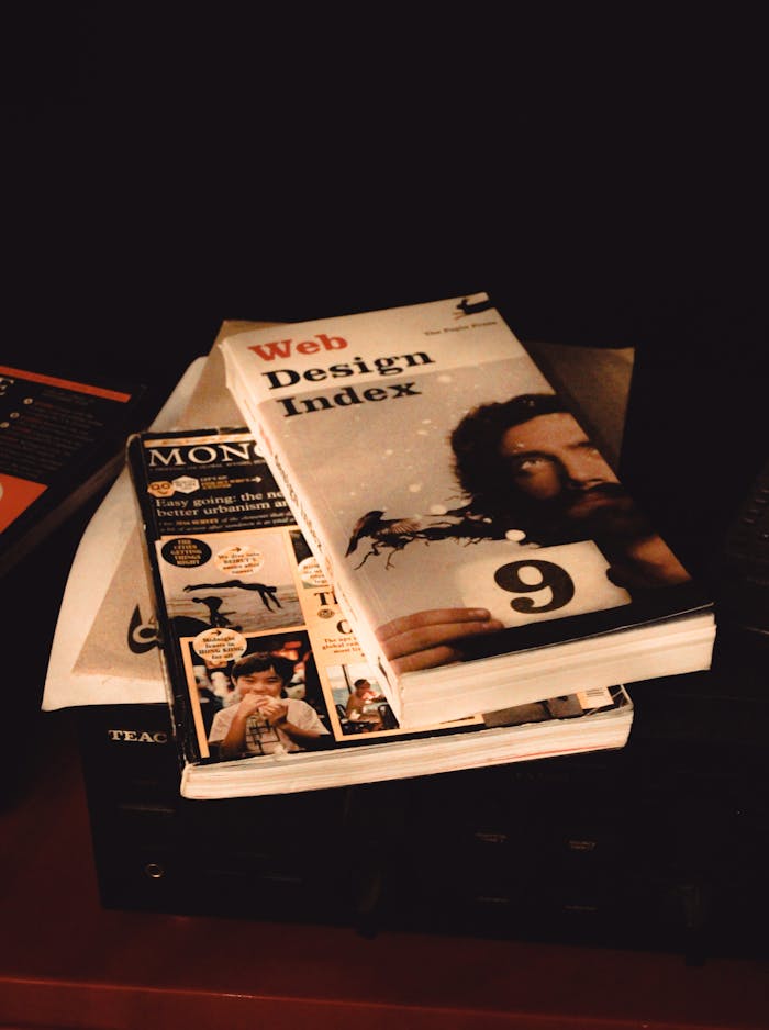 Stack of web design and media books on a shelf, emphasizing creative exploration.