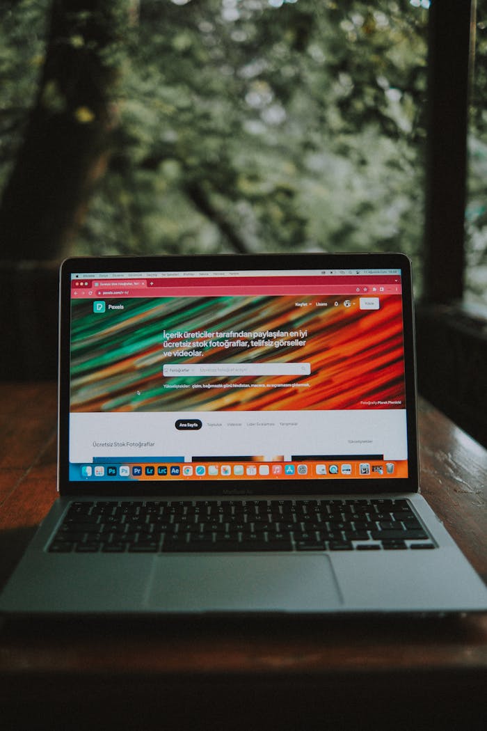 A laptop displaying a web browser sits on a wooden desk in an outdoor area.