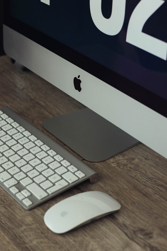 Big white desktop monitor and mouse with glossy surface on table with keyboard in adaylight